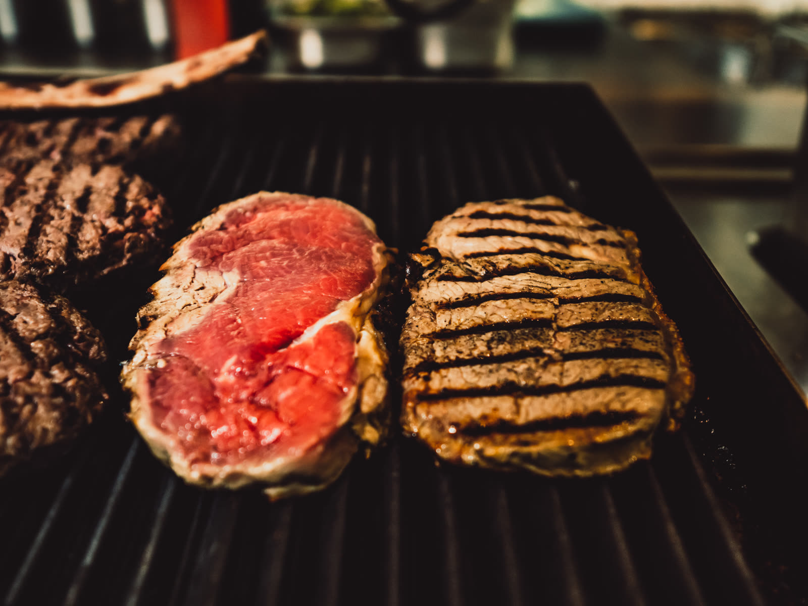 Ribeye-Steaks roh und gegrillt auf dem Grillrost